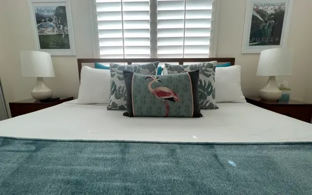King bed with a flamingo throw pillow and Palm Springs prints