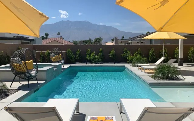 Pool with hanging egg chairs and mountain views