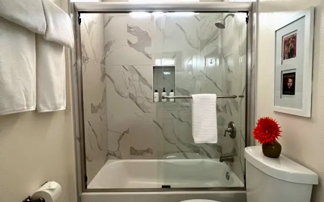 Marble-tiled shower and tub with fresh towels