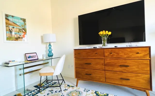 Desk nook with laptop, yellow roses and a second HDTV