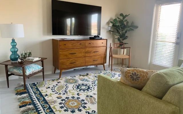The front room with a green sofa, mid-century dresser and wall-mounted HDTV